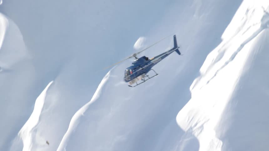A helicopter flies over a mountain