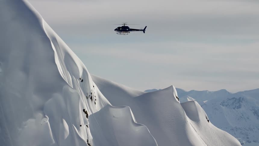 The helicopter flies above the mountains