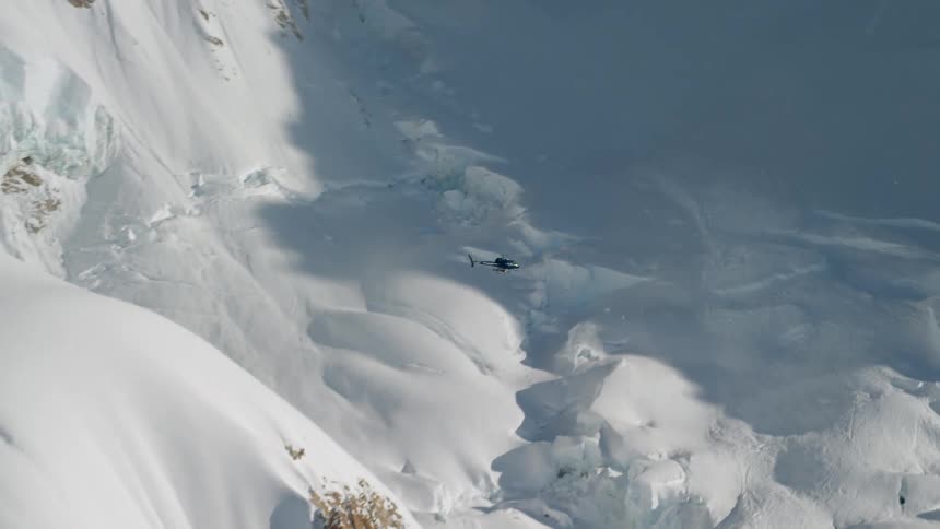 A helicopter flying over snow covered mountains
