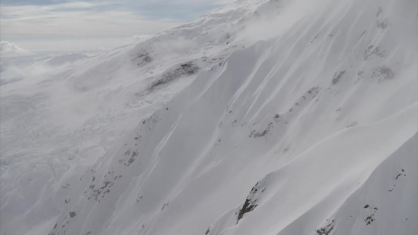 The clouds touch the top of the snow covered mountain