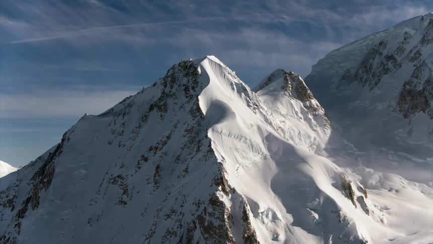 A rocky mountain ridge covered with snow on a bright blue sky day