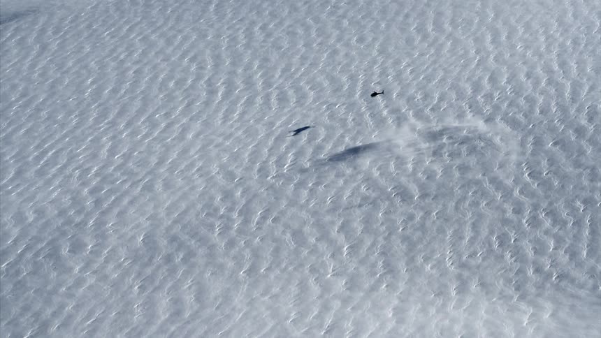 The helicopter takes off from the snow