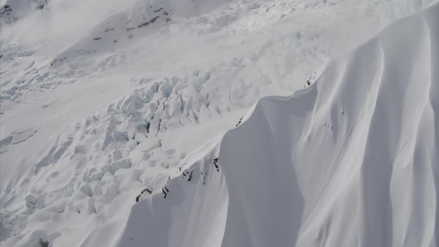 A snow covered mountain ridge gives way to an icy valley