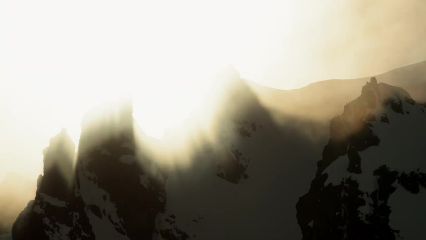 Fog obscures sunlight and snow covered mountains