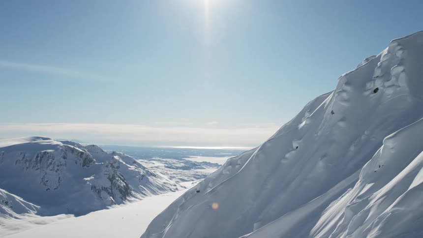 The sun shining down on a snow covered mountain valley in the arctic