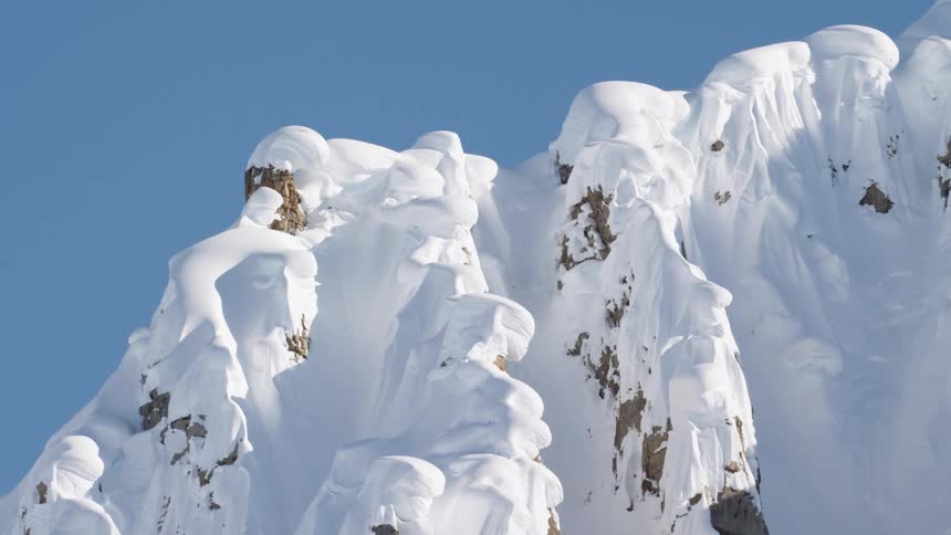 A snow covered mountain ridge against a bright blue sky