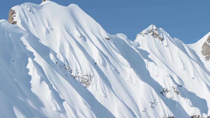 A mountain range covered in snow with the sky in the background