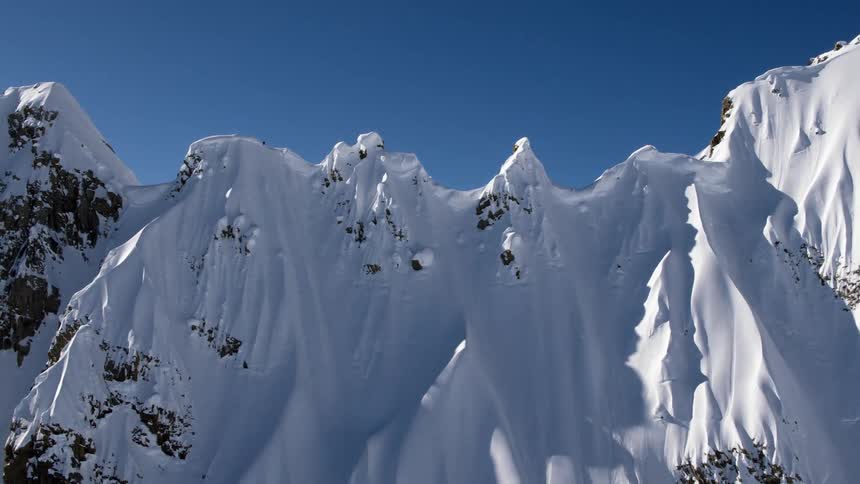 A snow covered mountain ridge under a blue sky