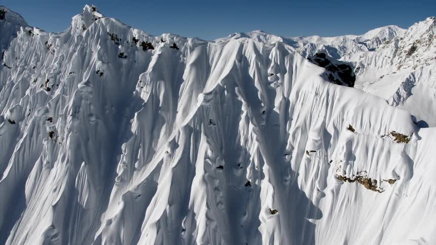 An aerial view of a mountain covered in snow is displayed