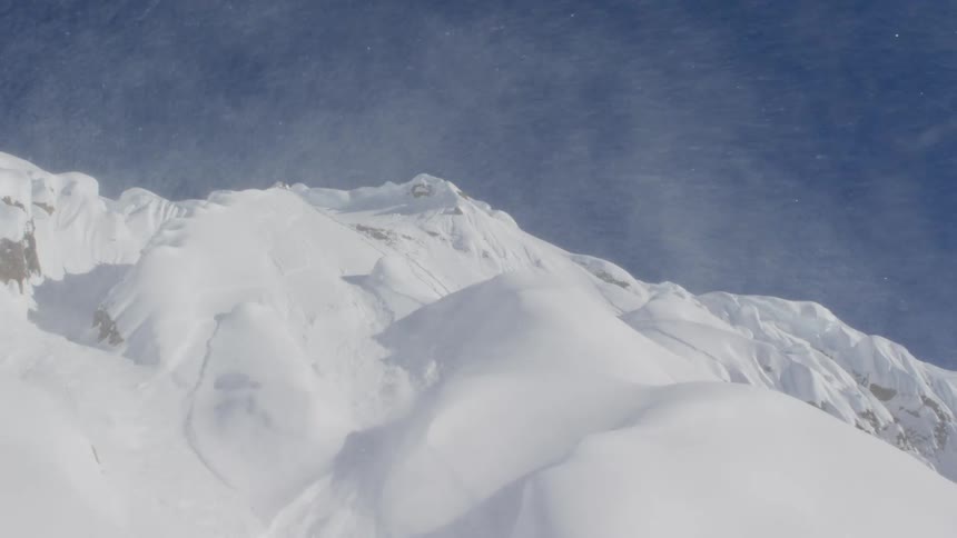 Snow blowing over a snow covered mountain