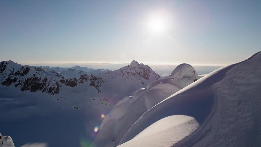 The sun shines over snow covered peaks of mountain range