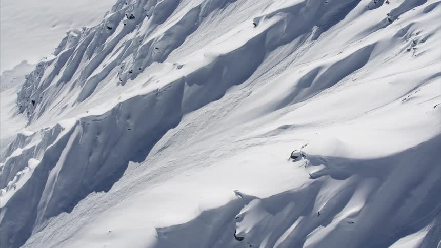 The slope of a mountain is covered in deep snow drifts