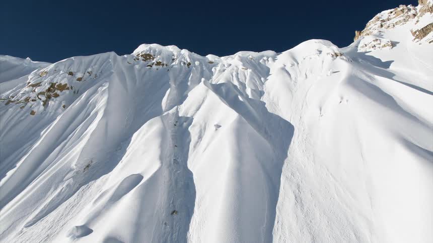 A snow covered cliff of a mountain rises straight into the sky