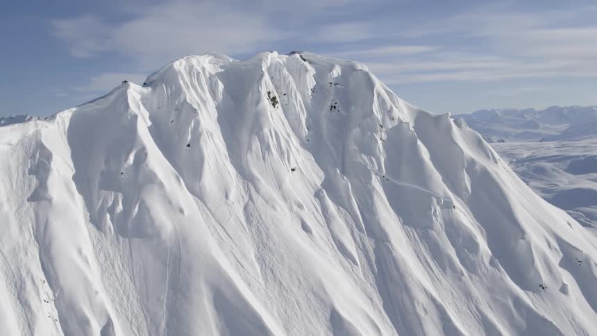 A snow covered mountain ridge with steep slopes in a frozen landscape on a bright sunny day