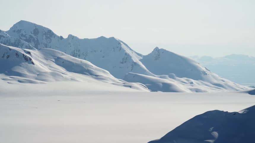 Snow covers a mountain range and a valley in deep drifts