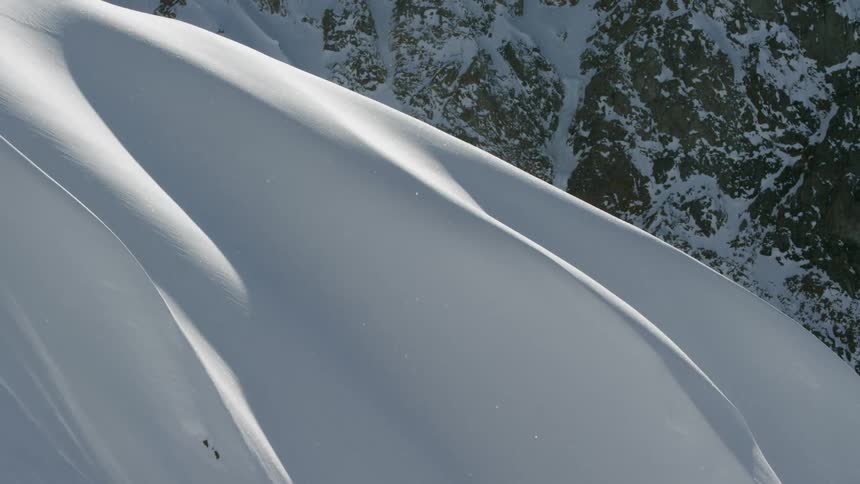 Huge snow drifts cover a mountain slope