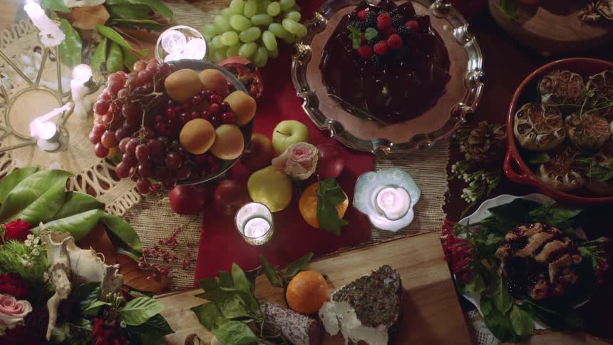 A table is set with platters and plates of various foods with candles and decorations