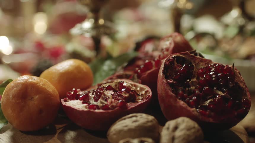 Open pomegranate with other fruits and nuts on the surface of a table