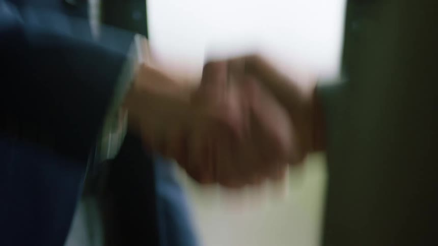 Two people shake hands by the window