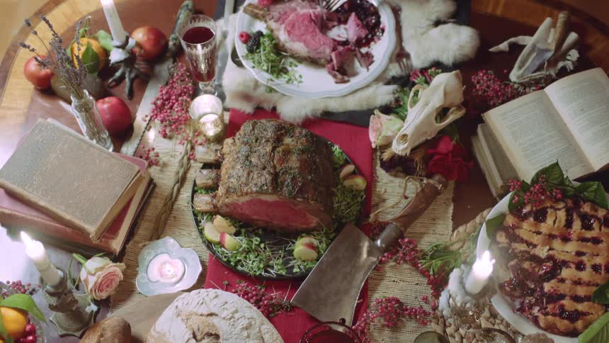 A woman cuts into steak sitting at a large table of food