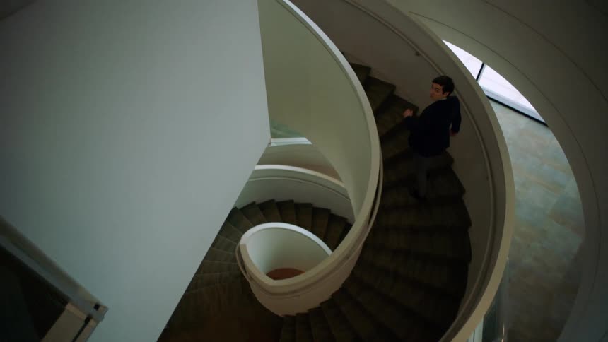 Man walking upstairs on a spiral staircase in a building