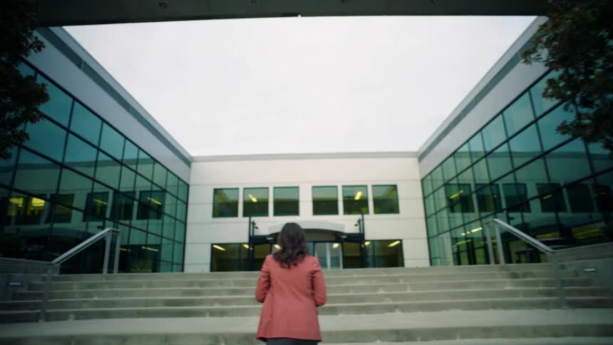 A woman walking up a staircase towards the entrance to a building