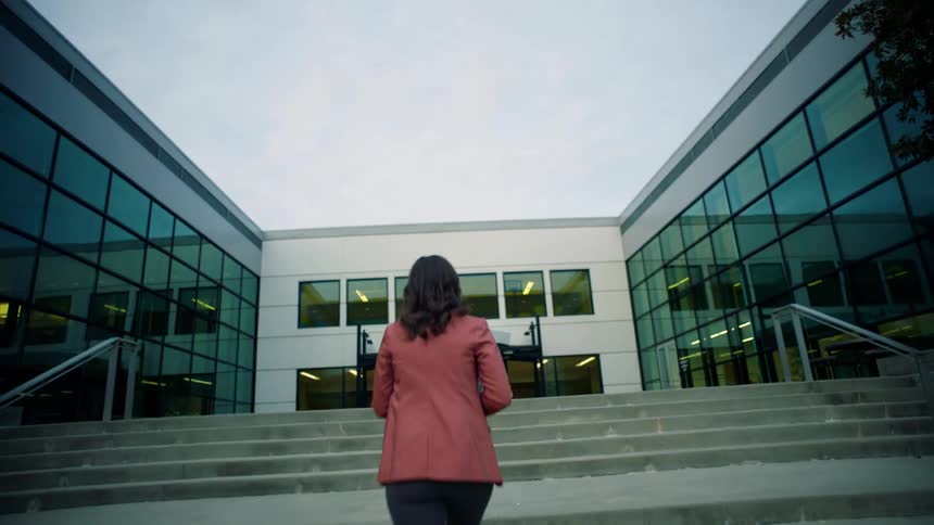 A woman walks towards the building on campus