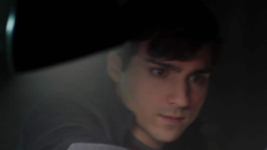 A young white male studies and then picks up a football helmet off of his desk