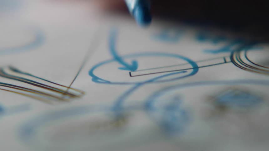 A white person draws a diagram with a blue marker