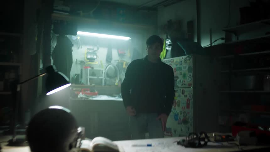 A man walking up to a desk sitting down and picking up a component