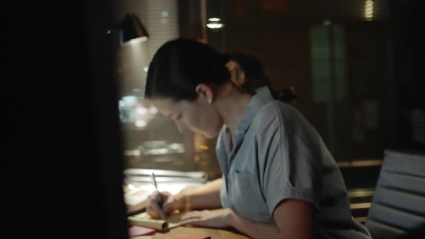A white woman goes through papers at her desk in an office