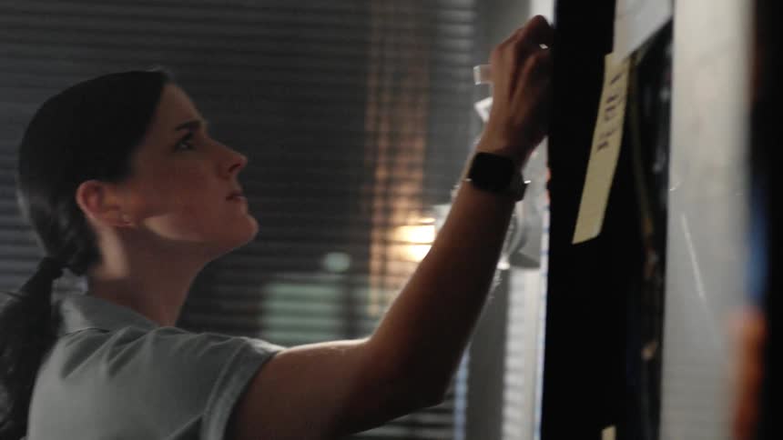 A woman writing on a whiteboard in an office at night