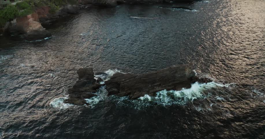 Aerial view of waves crashing on rocks in tropical island