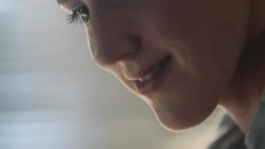 A woman holds a pen to her nose as she studies something below camera