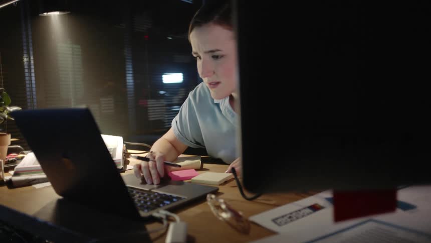 A white woman works at her office desk with determination