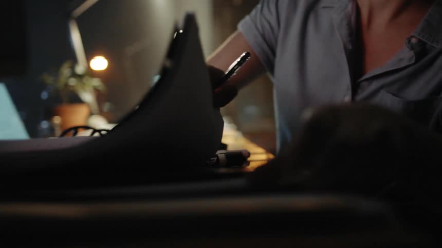 A white woman working in an office rummages around on her desk looking for something