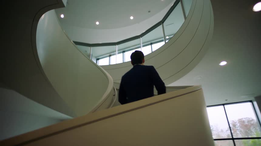 A man in a suit hustles up a staircase in an office building