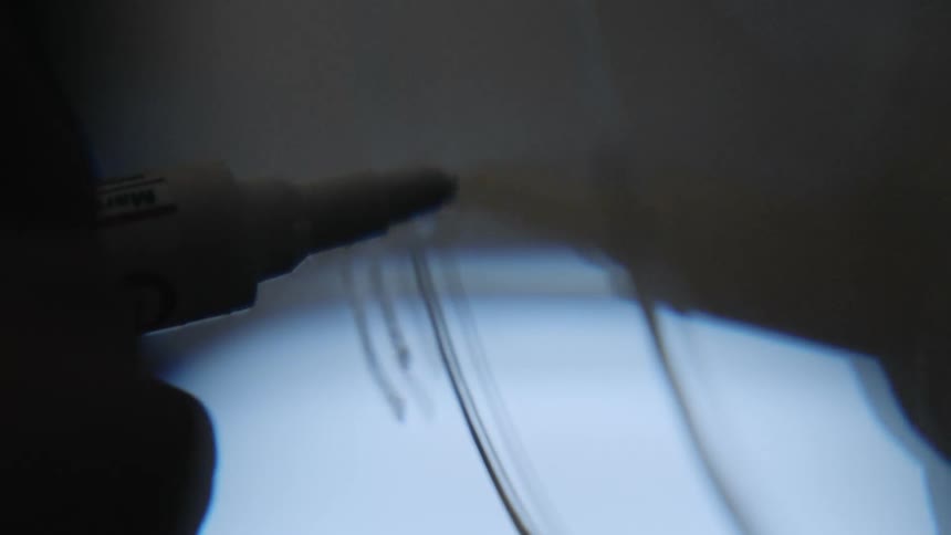A person writes on a glass surface with a marker