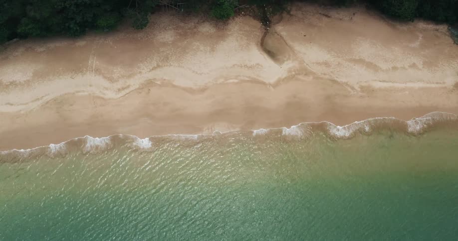 Aerial of gentle waves lapping at shoreline in a hidden cove
