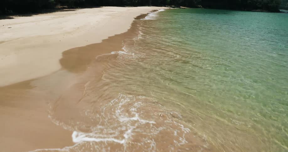 Aerial of waves crashing on tropical island beach