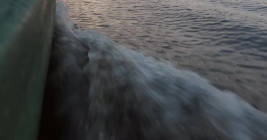 A boat hull cuts through a body of water and throws off a wake
