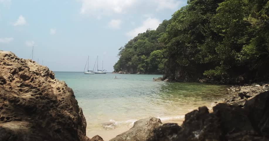 Tropical beach with waves and sail boats