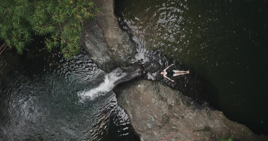 Aerial of woman swimming in rainforest river