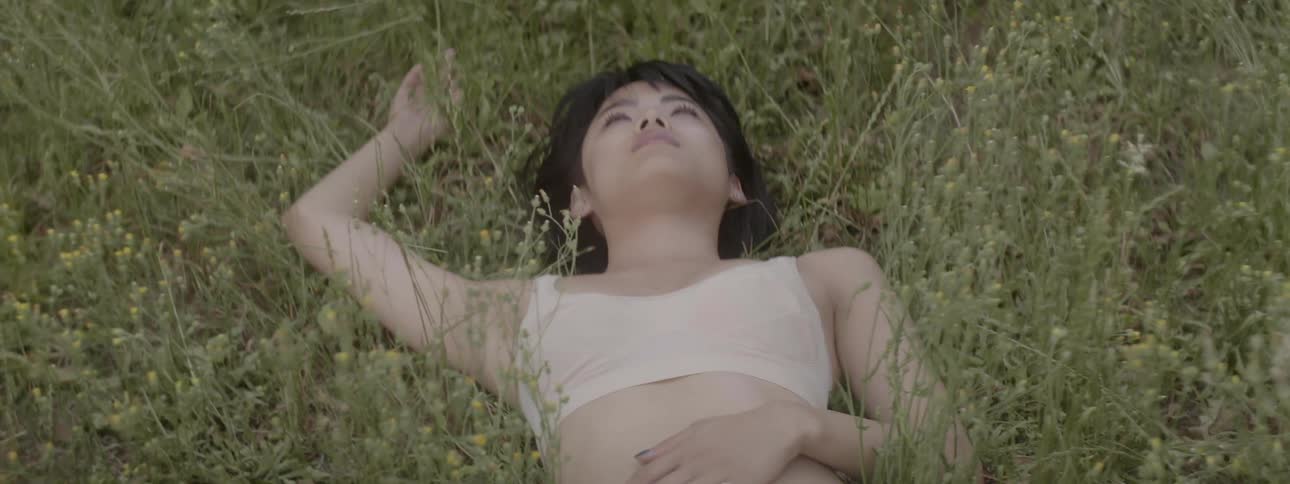 Young woman laying in field looking up at sky