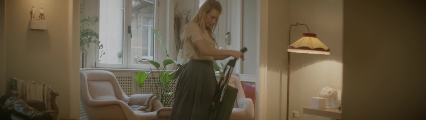 Blonde woman dances while vacuuming the living room