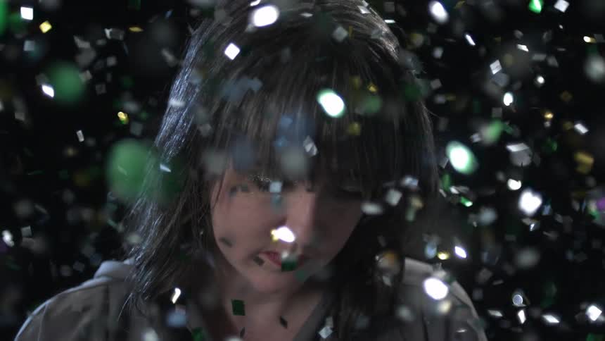 Glitter drops and flares around the head of a white woman standing still