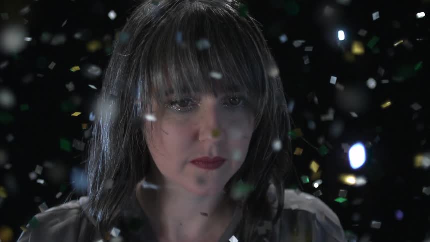 Sparkling confetti falls all around a woman