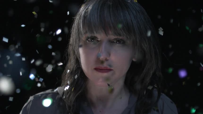 Close up of a womans face surrounded by falling glitter