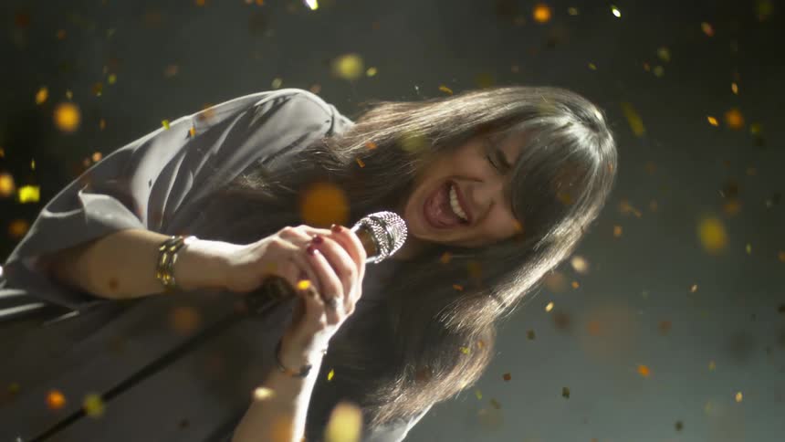 A woman singing in to a microphone