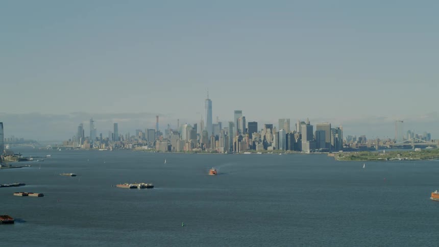 A large downtown area sits on the shores of a body of water filled with different types of watercraft